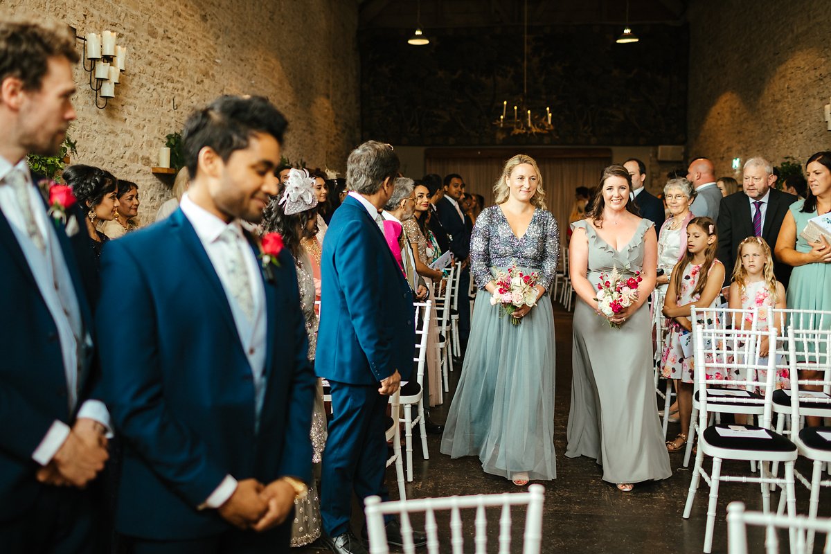 Bridesmaids walking down the aisle in grey dresses