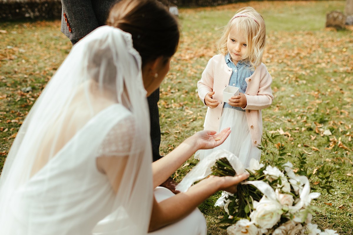 Cute flower girl is giving a gift to the bride